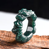 Cyan Jade Dragon Ring on dark wood, carved dragon head, backlit teal translucency, success talisman