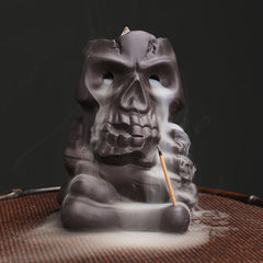Skull Head Purple Clay Incense Burner – smoke cascading from eye sockets over woven mat, backflow incense