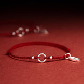 Sterling Silver Lotus Peace Buckle Red String Bracelet – Red braided cord bracelet with sterling silver peace buckle ring, flanking beads, and oval charm on a matching red background