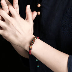 Tibetan Turquoise Om Mani Padme Hum Braided Bracelet – Worn on wrist with traditional garment, turquoise centerpiece visible