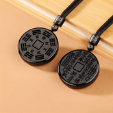Obsidian Bagua Pendant – two black carved pendants on peach background, trigram and calligraphy sides