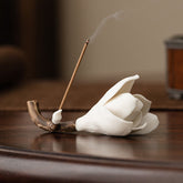 Gardenia Ceramic Incense Burner – White magnolia flower on brown branch with lit incense stick, dark wood table