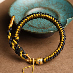 Tibetan Black Gold Dragon Scale Bracelet – three-quarter view with turquoise ceramic bowl, gold bead with blue mantra