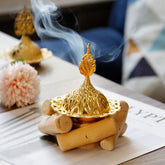 Gold Alloy Mini Incense Burner – ornate filigree dome lid with rising smoke on natural wood logs, incense burner home decor