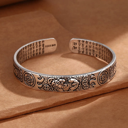 Sterling silver feng shui Pixiu cuff bracelet with lucky coin patterns, engraved Heart Sutra text and oxidized vintage finish on kraft paper