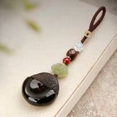 Pixiu Keychain – ice obsidian disc with brown cord and jade cloud on beige book, protection amulet