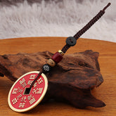 Shan Gui Keychain – red coin charm with gold border on brown cloud cord, driftwood display base