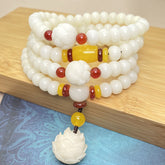 Lotus Bodhi Seed Mala 108 Beads - coiled white beads with lotus pendant on wood, bodhi mala bracelet