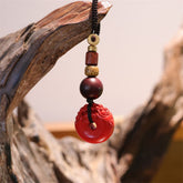 Cinnabar Peace Buckle Keychain – Red carved PiXiu pendant hanging on driftwood branch with beads