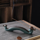 Double Koi Fish Mountain Incense Burner - teal wave holder with bronze koi and rising smoke on gray mat, koi incense burner