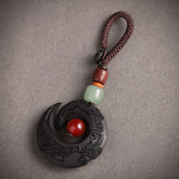 Feng Shui ebony wood protection keychain spiral crescent design with red agate bead on white background