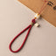 Bodhi Maneki Neko phone strap in wine red cord with carved cat bead charm and wristlet loop