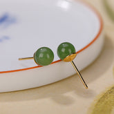 925 Silver Cyan Jade Healing Stud Earrings – apple green jade studs on blue floral porcelain dish, gold bezel settings, macro close-up