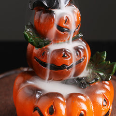 Stacked pumpkin backflow burner with ghost, thick white smoke cascading through carved faces, green leaves, dark bokeh – backflow incense holder