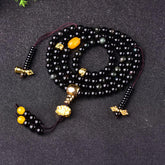 Black Obsidian Lotus Mala Bracelet - Coiled on dark fabric, glossy black beads with gold accents, obsidian