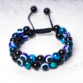 Evil Eye Hematite Tiger Eye Bracelet – double-row black tiger eye beads with blue evil eye charms, white background