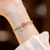 Red Agate Jade Lotus Bracelet – dusty blue gold cord with pink and green beads, lotus charm, worn on wrist lifestyle shot