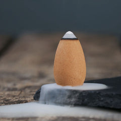 Mixed Aroma Backflow Incense Cones – Single cone on stone with white smoke waterfall flowing down, backflow cones