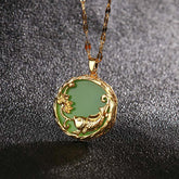 Gold koi fish lotus green jade pendant necklace, round cabochon stone in ornate gold plated setting with carved carp and lotus flower on twisted chain