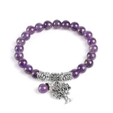 Tree of Life amethyst bracelet with purple gemstone beads, antique silver Tree of Life pendant with branches and roots, silver floral spacers on white background.