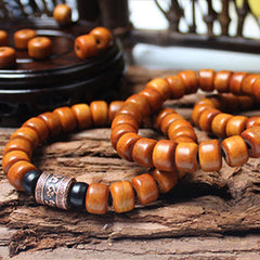 Tibetan Bone Beads Om Mani Padme Hum Bracelet – two stacked wood bead bracelets with copper charm on bark, meditation jewelry
