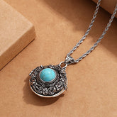 Tibetan Pi Xiu Necklace – Ornate silver locket with turquoise stone on brown paper
