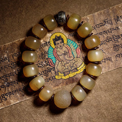 Tibetan Sheep Horn Skull Bracelet – Overhead view on Tibetan manuscript, amber beads with metal accents