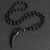 Ice obsidian wolf tooth pendant necklace with carved dragon head on polished black fang-shaped obsidian pendant with gold accent bead on knotted black bead cord