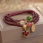 Garnet strawberry quartz triple-wrap bracelet with fox head charm red cabochon stone and zhao cai wealth-attracting tag on champagne satin jewelry box gift presentation