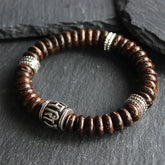 Om Mani Padme Hum Coconut Shell Bracelet – three-quarter view on dark stone, beaded bracelet