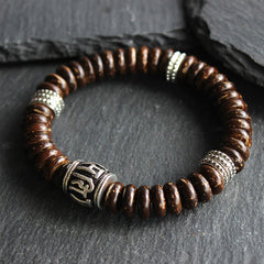 Om Mani Padme Hum Coconut Shell Bracelet – three-quarter view on dark stone, beaded bracelet