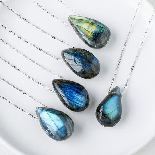 Labradorite water drop pendant necklace collection showing five natural labradorite teardrop pendants with blue green and gold iridescent labradorescence flash on silver chains in white ceramic dish