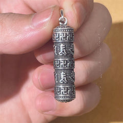 Copper Om Mani Padme Hum Necklace – Hand-held close-up of cylindrical pendant showing carved swastika borders and Sanskrit mantra bands, oxidized silver spiritual jewelry