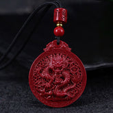 Vermilion red cinnabar dragon pendant necklace with carved Chinese dragon medallion, black cord and gold accent bead on dark background