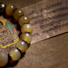 Tibetan Sheep Horn Skull Bracelet – Low angle on thangka manuscript, translucent amber bead close-up