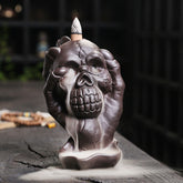 Skull Ghost Hand Incense Burner – skull cradled by skeletal hands with smoke waterfall, backflow incense