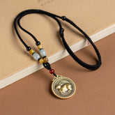 12 Chinese Zodiac Fortune Necklace Pendant – Rabbit zodiac medallion pendant in antique gold brass with raised rabbit relief, Greek key border, black braided cord with jade amber and carnelian beads, warm tan background, lunar new year jewelry gift