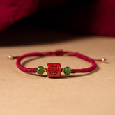 Tibetan Cinnabar Braided Rope Bracelet – Front view of carved red bead with green jade accents, red string jewelry