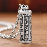 Om Mani Padme Hum Silver Protection Necklace – Antique silver cylindrical pendant with engraved Tibetan mantra script and spiral cloud scrollwork on cable chain, displayed on warm wood surface