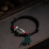 925 Sterling Silver Koi Fish Bracelet – silver koi charm on dark wooden tray, red thread wraps and green tassel, moody