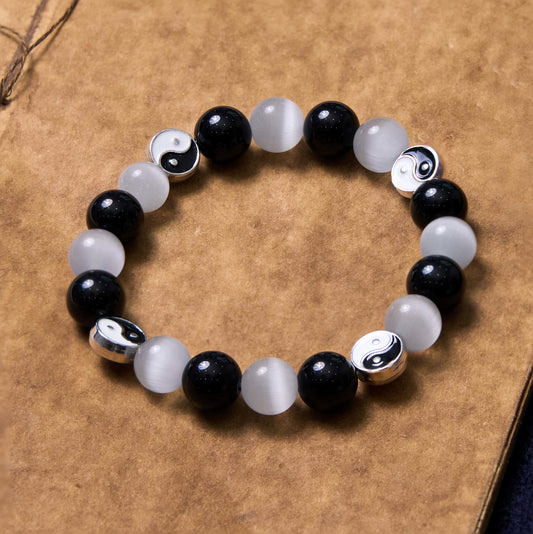 Black Obsidian Cat Eye Yin Yang Bracelet - alternating black obsidian and white cat eye beads with silver yin-yang spacers flat lay, yin-yang bracelet