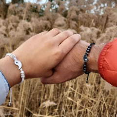 Yin Yang Hematite Bracelet - Black & white couple bracelets on clasped hands outdoors, friendship jewelry