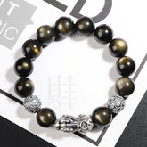 Gold Sheen Obsidian PiXiu Bracelet – Black gold-sheen beads with silver PiXiu on white magazine backdrop, wealth