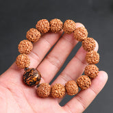 Rudraksha PiXiu Bracelet – Hand holding bodhi seed bracelet with carved copper coin bead, gray background