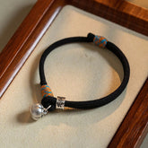 Om Mani Padme Hum Bracelet - Black cord with silver mantra bead and bell on wooden tray, Tibetan charm
