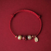 Hetian Jade Cinnabar Lotus Bracelet – Red cord flat lay with carved lotus cinnabar bead and jade stones, lucky red bracelet