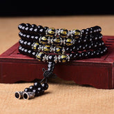 Black Obsidian Mala Bracelet - Coiled on carved wooden stand with gold mantra beads and silver spacers, obsidian prayer beads
