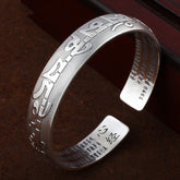 Tibetan Om Mani Padme Hum silver prayer bangle with raised Tibetan script exterior, Heart Sutra Chinese engraving inside, S999 fine silver on dark wood.