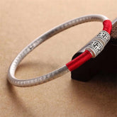 Tibetan Red String Bracelet – silver bangle with red cord and engraved sutra text, three-quarter view