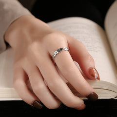 925 Sterling Silver Om Mani Padme Hum Ring – silver mantra ring worn on finger resting on open book, lifestyle jewelry